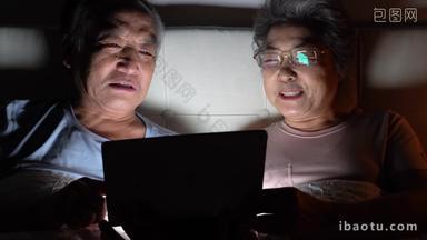 老年夫妇坐在床上使用平板电脑
