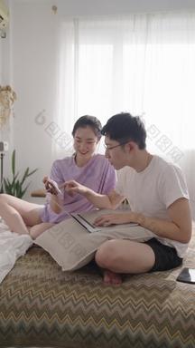 年轻情侣在家使用手机和电脑