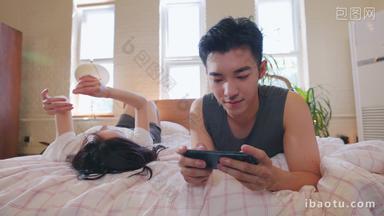 青年情侣趴在床上玩手机