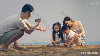 沙滩上青年男人为妻子孩子拍照