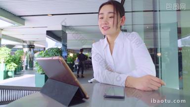 年轻女人坐在咖啡馆里使用平板电脑