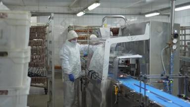香肠部门的工作人员站在真空包装香肠的自动包装装置旁边.