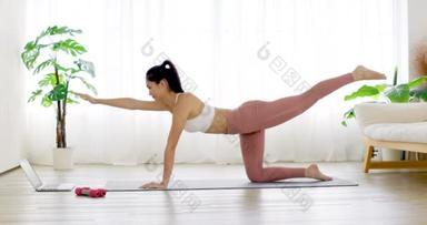 穿着运动服的年轻女子在家里做瑜伽垫运动训练