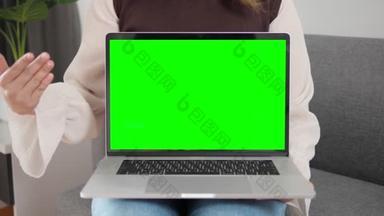 女人在家里的沙发上展示带有<strong>绿</strong>色<strong>屏</strong>幕和彩色键的笔记本电脑。显示<strong>绿</strong>色<strong>屏</strong>幕并与相机对话