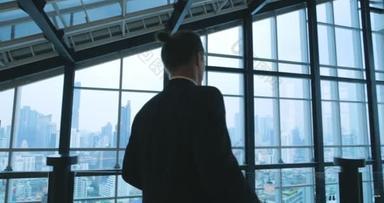 一个穿着西服、心事重重的商人站在他的办公室里，向窗外看建筑的城市景观的倒影.