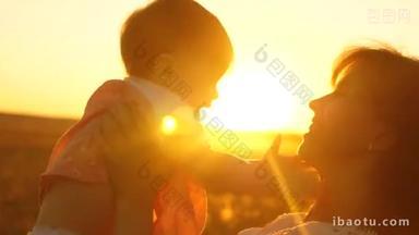 <strong>快乐</strong>的母亲在金色太阳的夕阳下玩耍着婴儿.