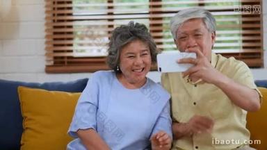亚洲老年夫妇使用智能手机进行<strong>视频</strong>聊天。分享<strong>社交</strong>媒体沟通坐在家里的坐。慢动作.