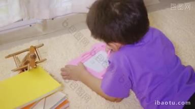 快乐的亚洲klid小男孩在家里的磁板上写在地毯上。有趣的孩子玩磁力画板。教育学习<strong>绘画</strong>概念。背景色