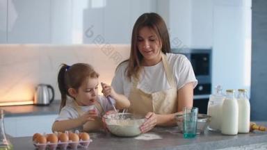 妈妈在教小女儿用打蛋器进行食材搅拌