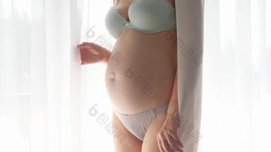 孕妇在纱窗前<strong>抚摸</strong>着她的肚子