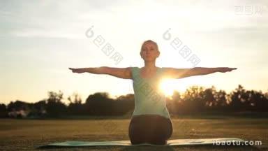 美丽的成人健身金发女人在<strong>绿色</strong>的草坪上练习<strong>瑜伽</strong>练习在令人惊叹的日落的辉光迷人的健身女士工作
