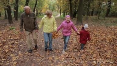 笑容满面的老夫妇和可爱的孙子孙女们在秋天的公园里散步，美丽的爷爷奶奶们一起享受闲暇时光