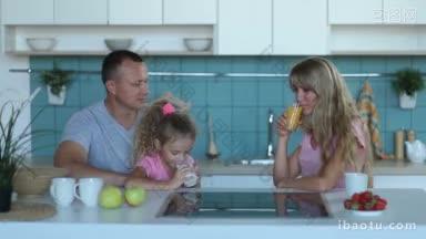 可爱的小卷曲的女儿喝<strong>牛奶</strong>，坐在父亲的腿上，在家庭早餐在厨房快乐的家庭与
