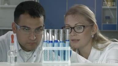 高级女科研人员和混合总状男同事在化学实验室讨论实验结果女科学家戴防护手套