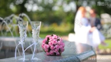 新娘花束和两杯香槟在喷泉附近的背景新婚夫妇