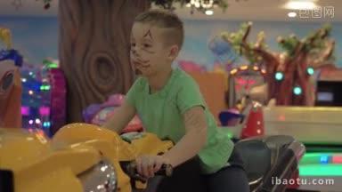 画着猫脸的男孩在室内游乐园玩<strong>摩托车赛车</strong>模拟器