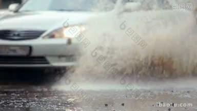 一辆轿车在被洪水淹没的街道上穿过一个大水坑，溅起水花