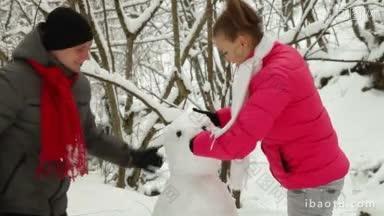 一对十几岁的<strong>情侣</strong>在冬天的雪林里堆雪人