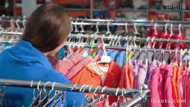一名年轻女子在服装店选购衣服，挑选童装