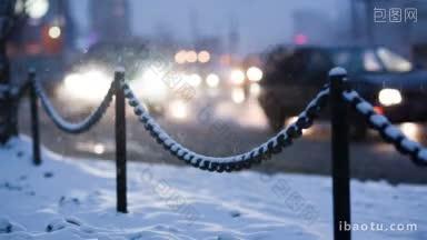 在一个冬天的夜晚，<strong>城市交通</strong>中，亮着大灯的散焦汽车缓缓驶过前景中的公路边界