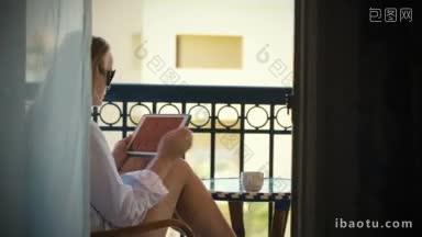 年轻女子在酒店阳台上用平板电脑喝茶的照片