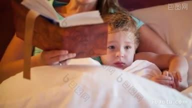 倾斜镜头的母亲和儿子在睡前阅读，妈妈大声朗读和孩子看电视