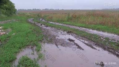 泥泞的土路，泥泞的水坑穿过雨中的田野