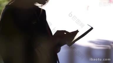 倾斜拍摄的妇女<strong>使用</strong>平板电脑黑色剪影对明亮的光线