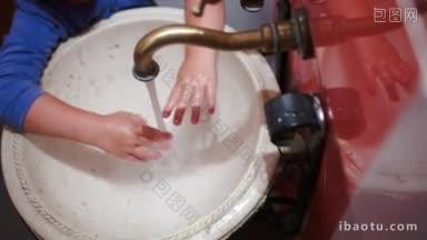 一个小孩在老式水槽里洗手，关掉水龙头的高角特写镜头