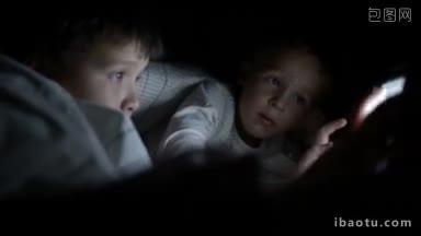 两个躺在床上的小男孩试图在晚上用平板电脑<strong>看电影</strong>