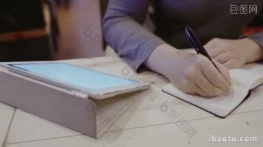 特写镜头一个女人在她的皮夹里做笔记坐在木制<strong>桌子上</strong>的触摸板