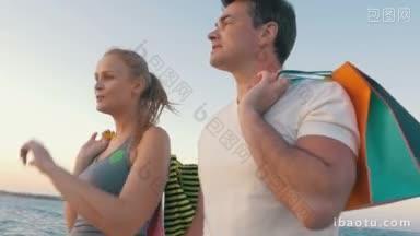 慢动作斯坦尼康拍摄的年轻夫妇走路和说话在海边的肩膀上包购物