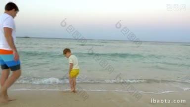 小男孩和他的父亲在海滩上的冲浪<strong>水中</strong>跳跃，和家人一起度过了美好的假期