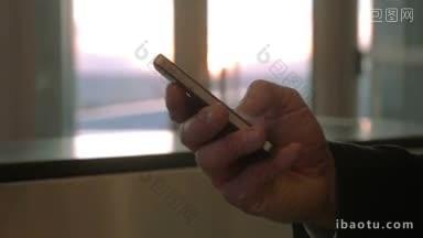 在机场，一名男子在手机上打字的特写镜头模糊了窗外的夕阳景色