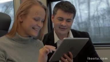 乘火车旅行的年轻男女在旅途中一边聊天一边用平板电脑娱乐自己