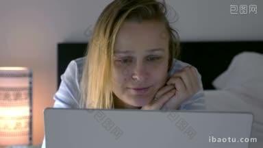 年轻的女人躺在床上的笔记本电脑在晚上她<strong>看电影</strong>引发的情绪悲伤和大笑