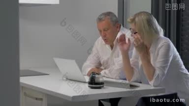 成熟的男人和女人用笔记本电脑和平板电脑在室内工作，他们在工作时喝咖啡