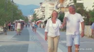 快乐的高级夫妇走在人行道上的度假村男子旋转一个女人和兴奋的夫妇继续的方式