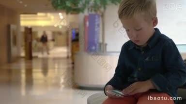 小男孩在购物中心翻看智能手机上的照片，不明身份的人经过