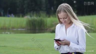 迷人的女商人工作与手机在公园外面的一个自由时间微笑的妇女自由使用手机户外