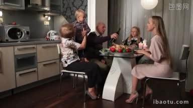 幸福的家庭和爷爷奶奶坐在客厅的餐桌上，享受着感恩节大餐，爷爷把酒倒进玻璃杯里