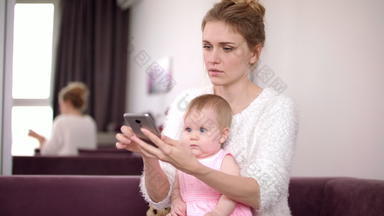女人婴儿持有电话首页工作妈妈。女日常生活
