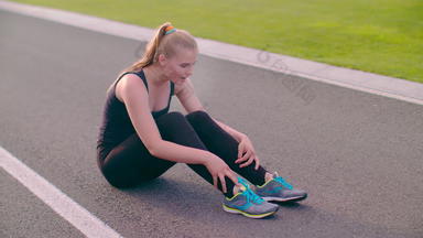 累了跑步者坐着沥青路疲惫女跑步者呼吸硬