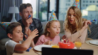 女孩吹<strong>蜡烛</strong>蛋糕父母家庭庆祝生日在线