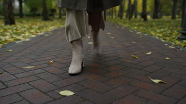女脚时尚的靴子10月公园女人腿走路径