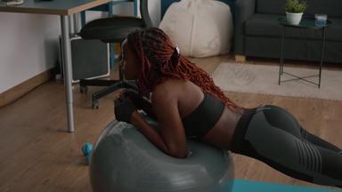 运动苗条的黑色的女人伸展运动腹部肌肉坐着瑜伽健身瑞士球