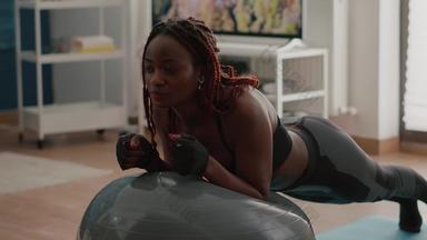 非洲苗条的女人条纹腹部肌肉坐着瑜伽瑞士球