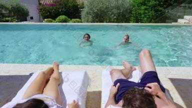 家庭孩子们放松在游泳池边