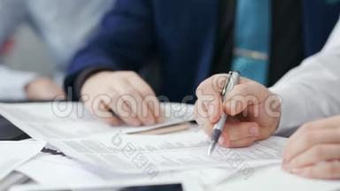 团队会议期间，两位商人手持钢笔，在纸质<strong>文件</strong>上<strong>展示</strong>细节