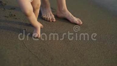 一个小婴儿<strong>赤脚</strong>走在沙滩上。 妈妈教孩子<strong>走路</strong>..